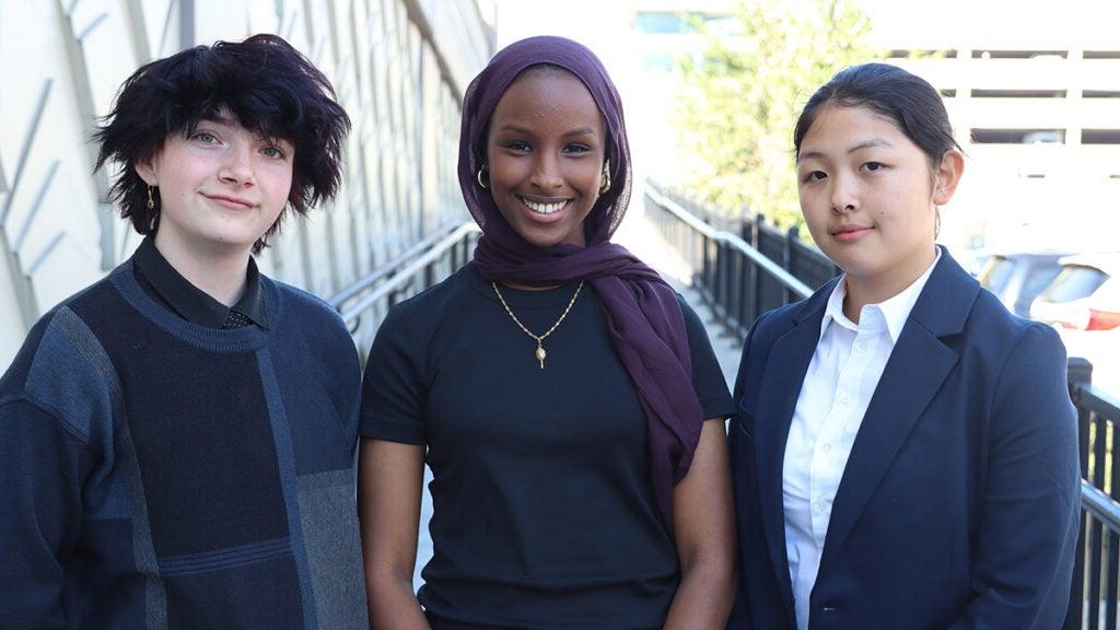 The three student board members pose for a photo outside.